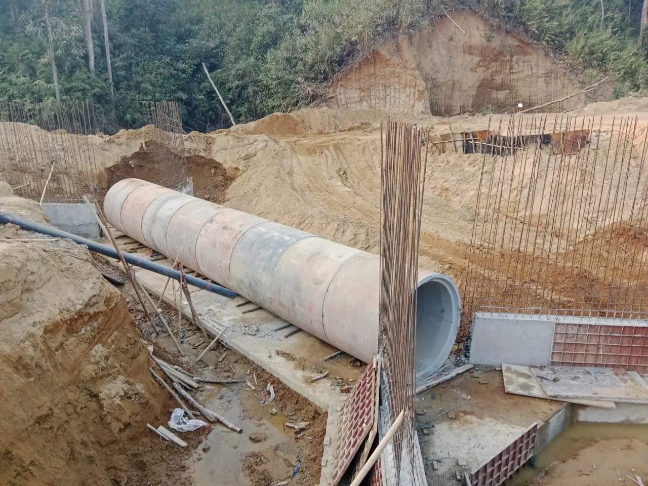 Precast RCC pipe sections laid on a concrete bed between rebar cages and steel formwork for culvert walls