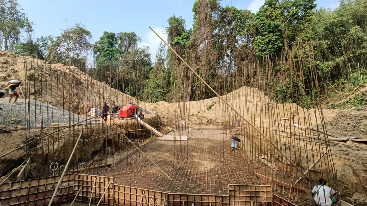 Wide view of rebar mesh and vertical starter bars for a culvert base slab in a forested hillside cutting